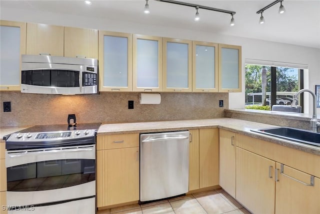 kitchen with light brown cabinets, light tile patterned floors, stainless steel appliances, and sink