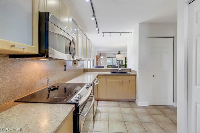 kitchen with light tile patterned floors, tasteful backsplash, black range with electric stovetop, and sink