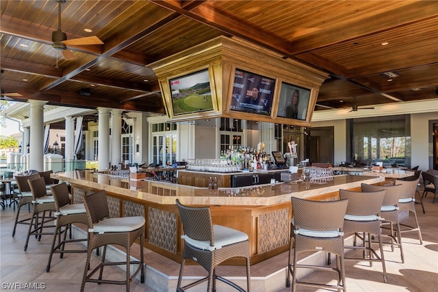 bar featuring plenty of natural light, wooden ceiling, and ornate columns