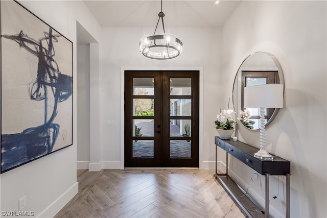 entrance foyer with french doors, a notable chandelier, and light parquet floors