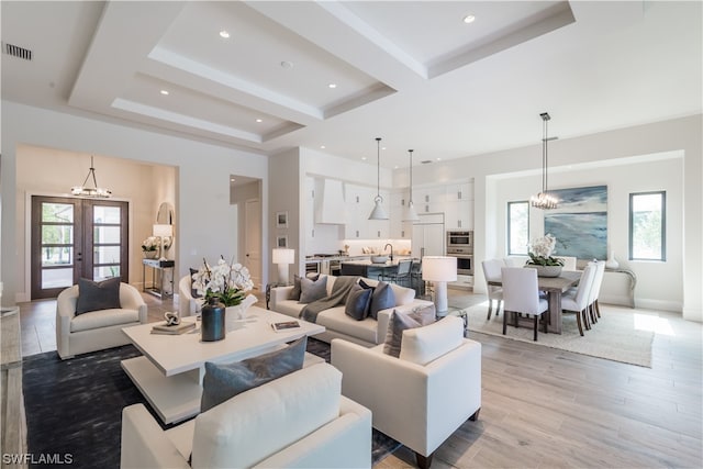 living room with light hardwood / wood-style flooring, a wealth of natural light, french doors, and a chandelier