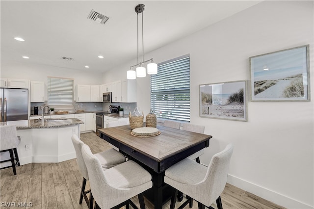 dining space with light hardwood / wood-style flooring and sink