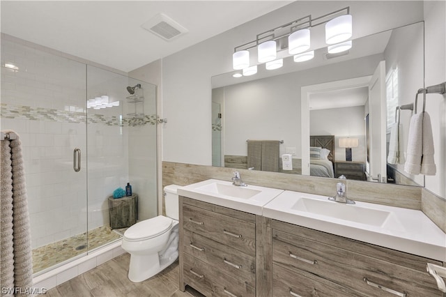 bathroom with double sink vanity, toilet, a shower with door, and hardwood / wood-style flooring