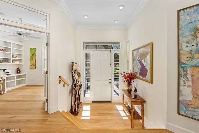 foyer with a wealth of natural light, crown molding, and light wood-type flooring