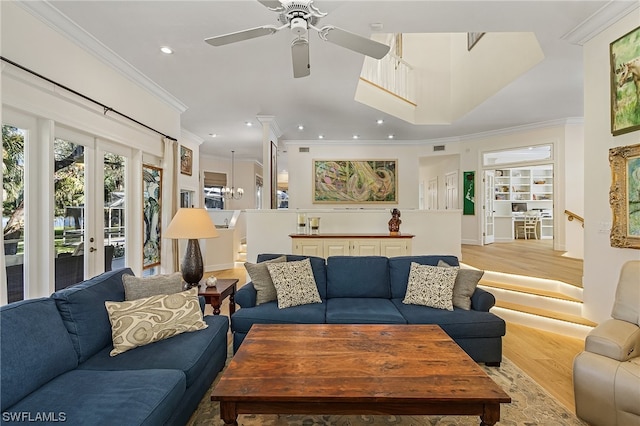 living room with ornamental molding, light hardwood / wood-style flooring, ceiling fan with notable chandelier, and french doors