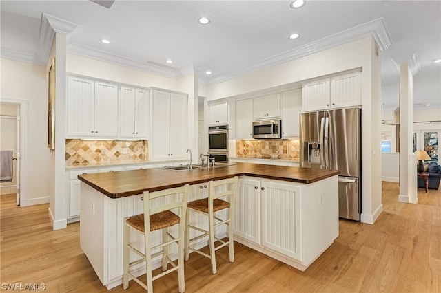 kitchen featuring backsplash, appliances with stainless steel finishes, a center island with sink, and light wood-type flooring