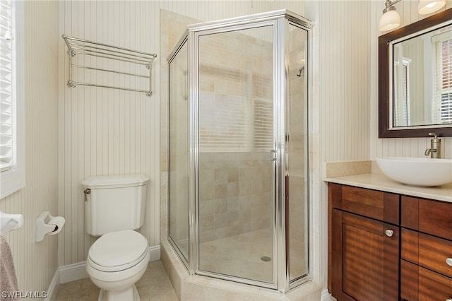 bathroom featuring tile flooring, vanity, toilet, and a shower with door