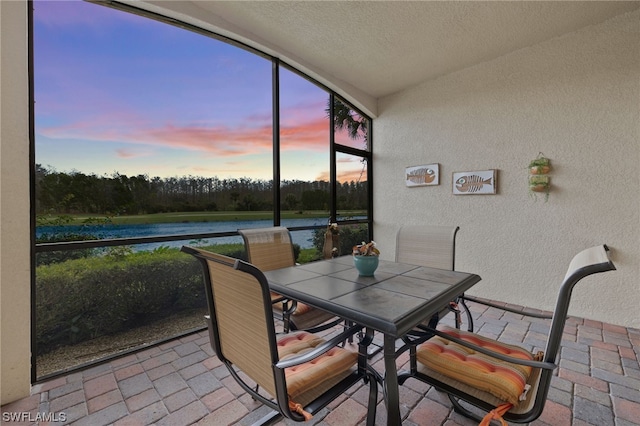 sunroom featuring a water view