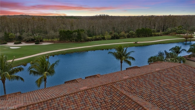 pool at dusk with a water view and a yard