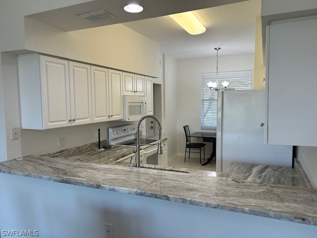 kitchen featuring decorative light fixtures, white cabinets, white appliances, light stone countertops, and a chandelier