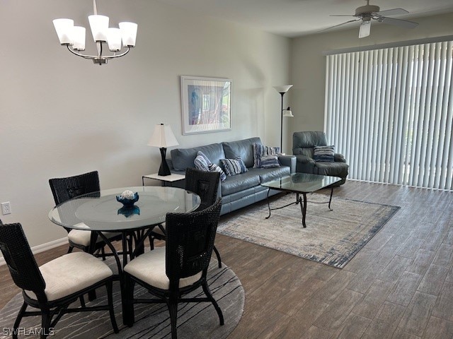 dining area with ceiling fan with notable chandelier and dark wood-type flooring