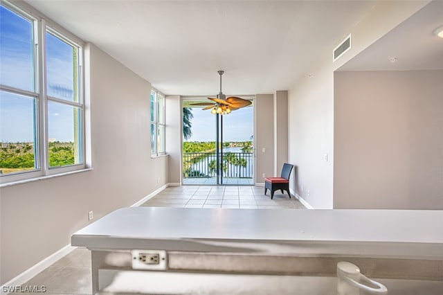 game room with ceiling fan, a water view, and light tile patterned flooring