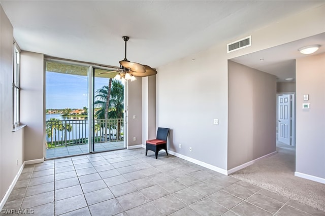 interior space with ceiling fan, light tile patterned flooring, a water view, and floor to ceiling windows