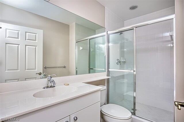 bathroom with an enclosed shower, vanity, and toilet