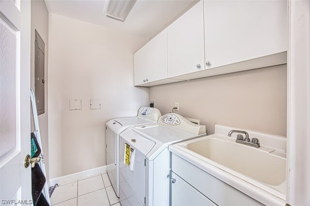 clothes washing area featuring washer and clothes dryer, sink, light tile patterned flooring, and cabinets