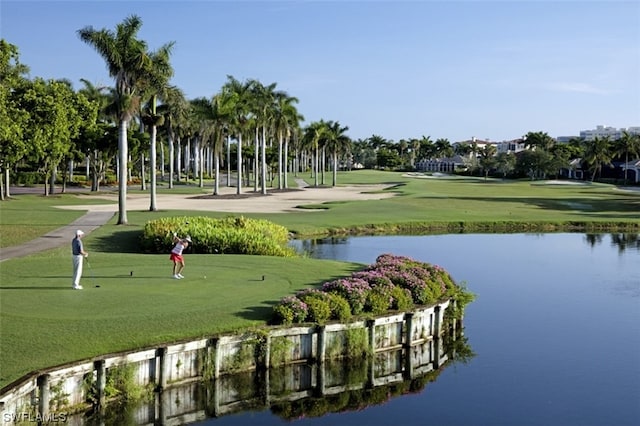 surrounding community with a water view and a lawn