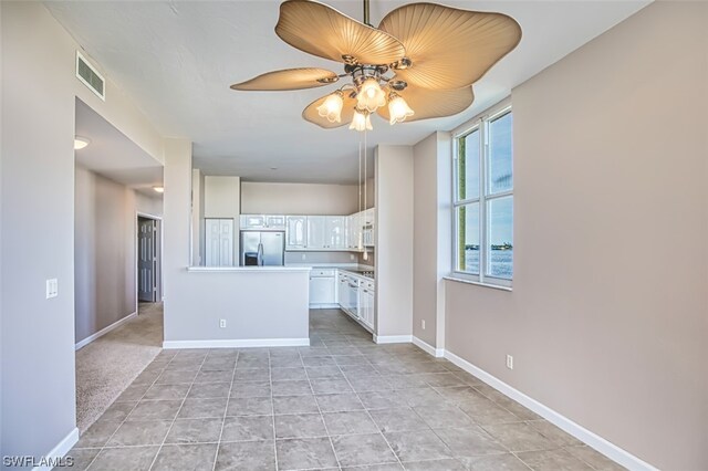 kitchen featuring light carpet, ceiling fan, stainless steel fridge, and white cabinetry