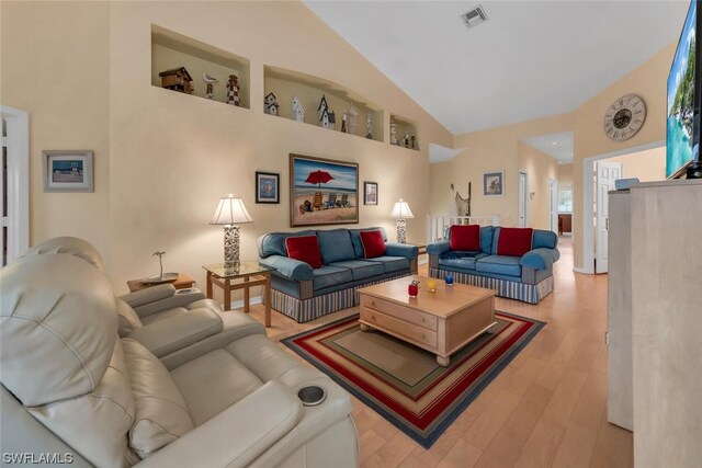 living room with light hardwood / wood-style floors and high vaulted ceiling