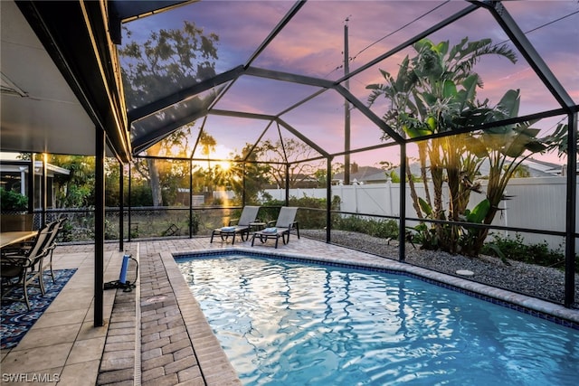 pool at dusk featuring a patio and a lanai