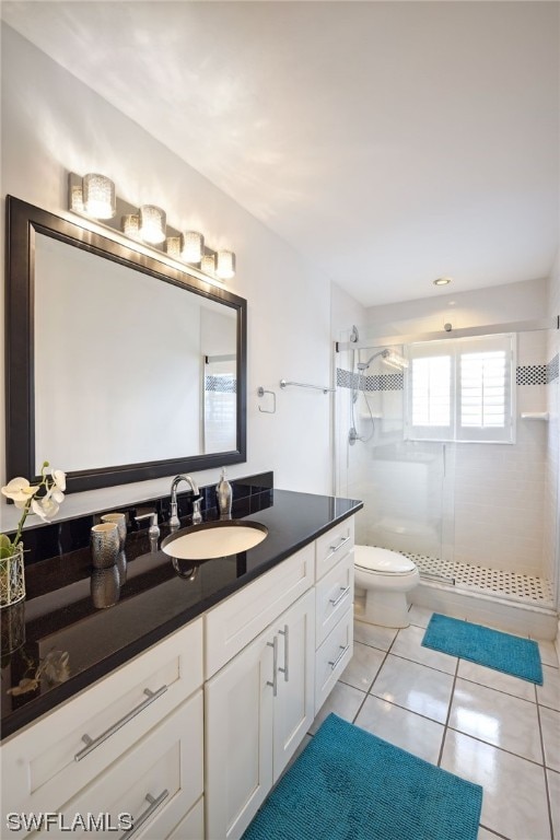 bathroom featuring vanity, tile patterned flooring, toilet, and tiled shower