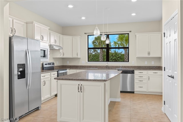 kitchen featuring stainless steel appliances, a kitchen island, hanging light fixtures, and white cabinetry