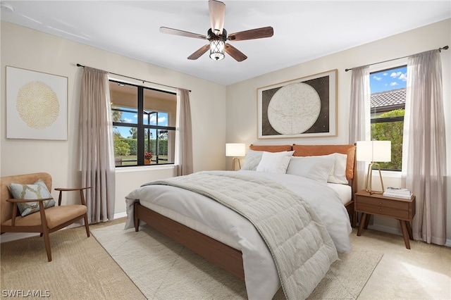 carpeted bedroom featuring ceiling fan and multiple windows