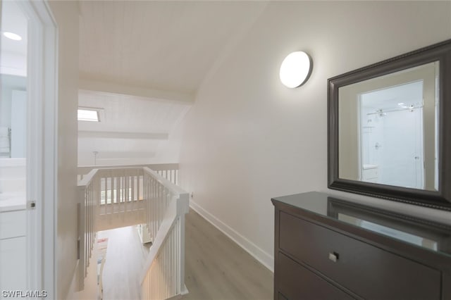 corridor with vaulted ceiling and hardwood / wood-style floors