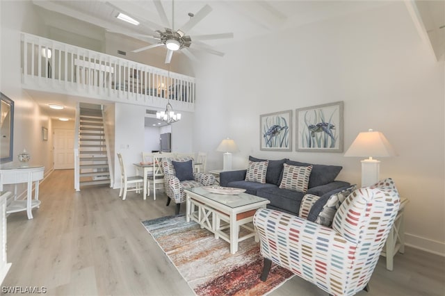 living room featuring hardwood / wood-style flooring, ceiling fan with notable chandelier, and a towering ceiling