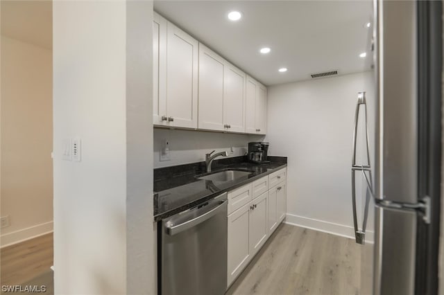 kitchen with white cabinets, dark stone countertops, appliances with stainless steel finishes, and sink