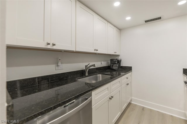 kitchen featuring dark stone counters, light wood-type flooring, sink, white cabinets, and stainless steel dishwasher