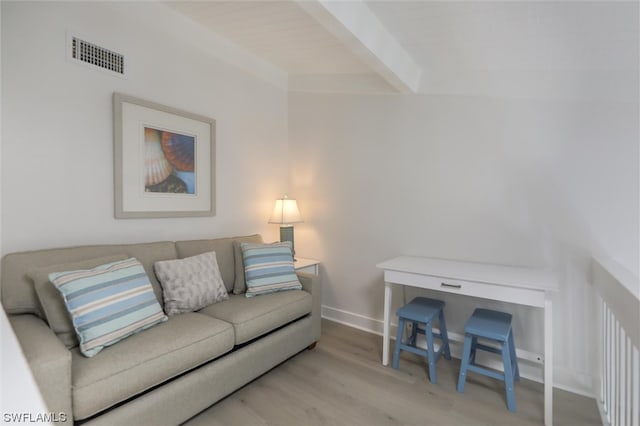 living room featuring beamed ceiling and light hardwood / wood-style flooring