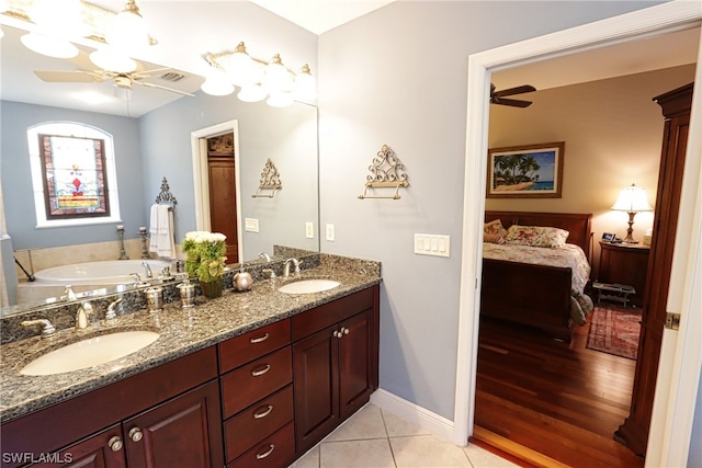 bathroom with dual vanity, a washtub, ceiling fan, and tile patterned flooring