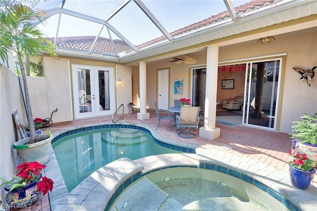 view of swimming pool featuring an in ground hot tub, french doors, a patio area, ceiling fan, and glass enclosure