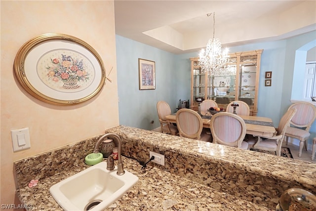 bathroom featuring an inviting chandelier, sink, and a tray ceiling