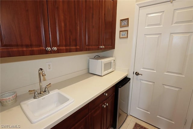 laundry area with sink, cabinets, light tile patterned floors, and wine cooler