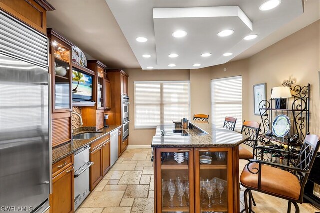 kitchen with appliances with stainless steel finishes, sink, and dark stone counters