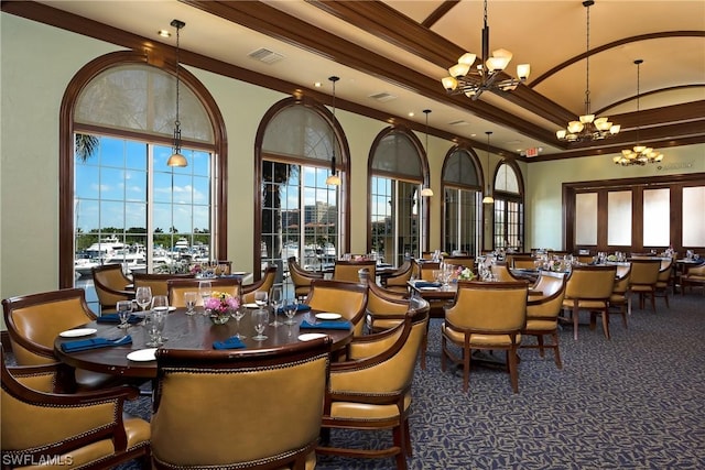 carpeted dining room featuring crown molding, a towering ceiling, a notable chandelier, and a healthy amount of sunlight