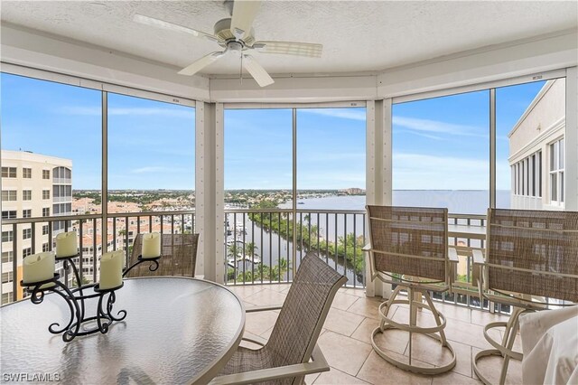 sunroom / solarium featuring a water view, plenty of natural light, and ceiling fan