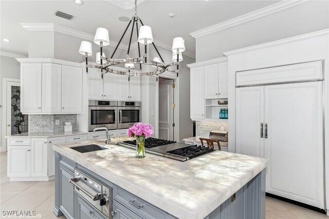 kitchen featuring paneled refrigerator, white cabinetry, and a kitchen island with sink