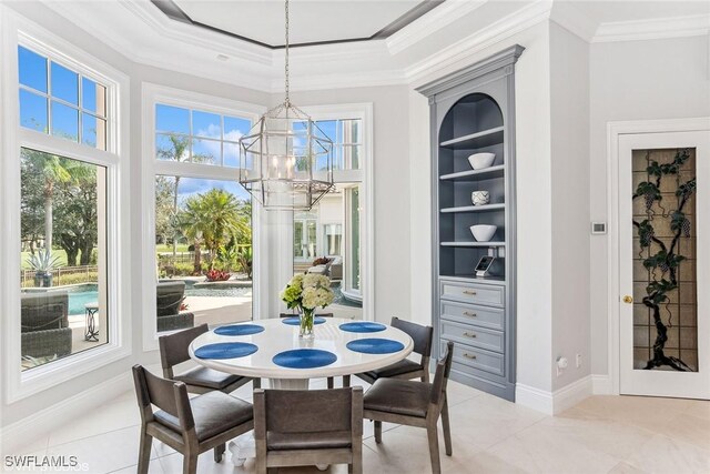 dining room featuring a tray ceiling, built in features, a chandelier, and ornamental molding