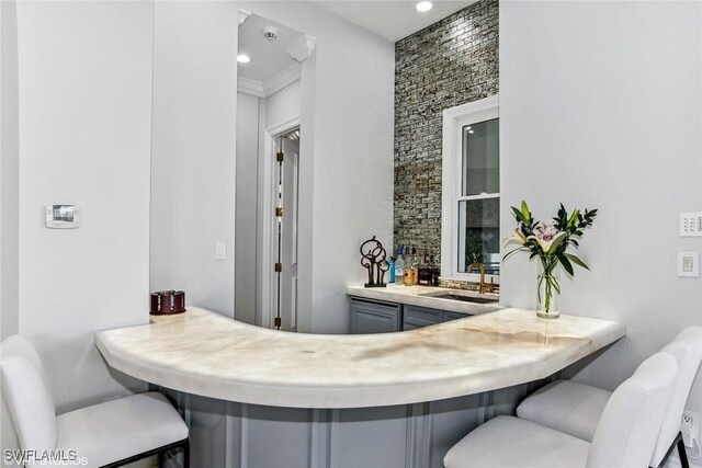 bar featuring gray cabinets, ornamental molding, and sink