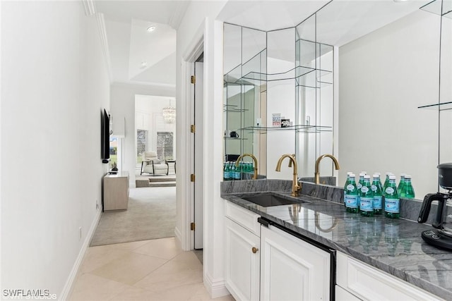 bar featuring baseboards, light colored carpet, ornamental molding, light tile patterned floors, and a sink