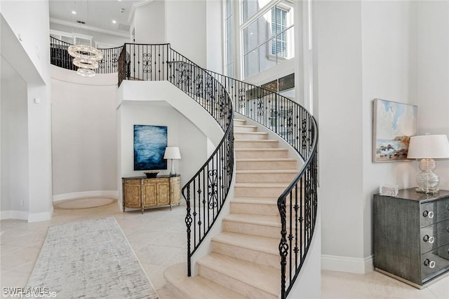 staircase featuring baseboards, a towering ceiling, crown molding, and tile patterned flooring