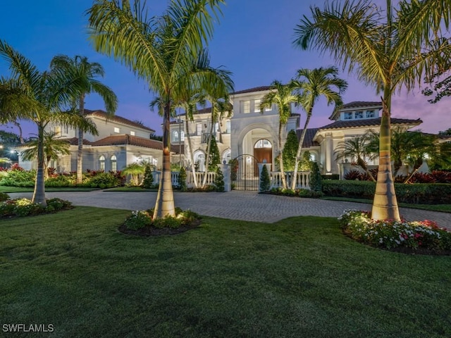 mediterranean / spanish-style house featuring decorative driveway and a front yard