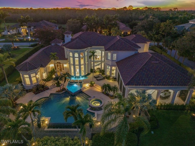 exterior space with stucco siding, a patio, an outdoor pool, an in ground hot tub, and a tiled roof