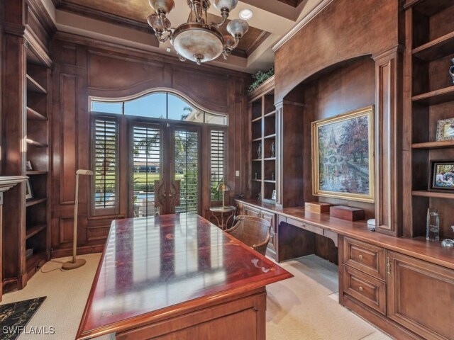 office featuring wood walls, light carpet, crown molding, built in desk, and a chandelier