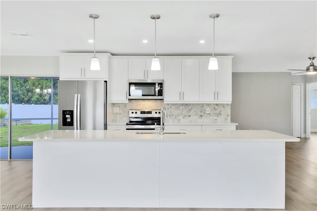 kitchen with an island with sink, stainless steel appliances, ceiling fan, light hardwood / wood-style flooring, and white cabinets