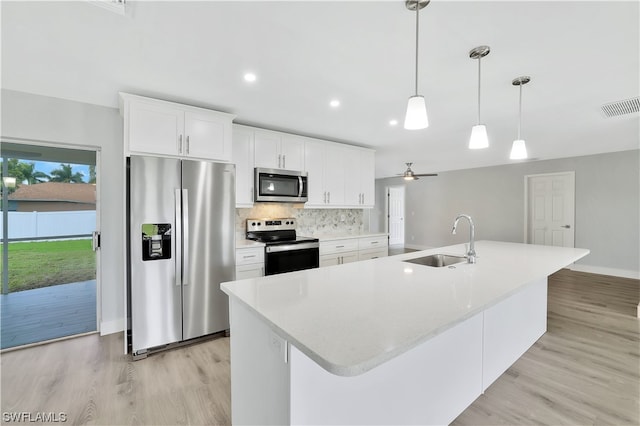 kitchen featuring sink, backsplash, stainless steel appliances, white cabinetry, and light wood-type flooring