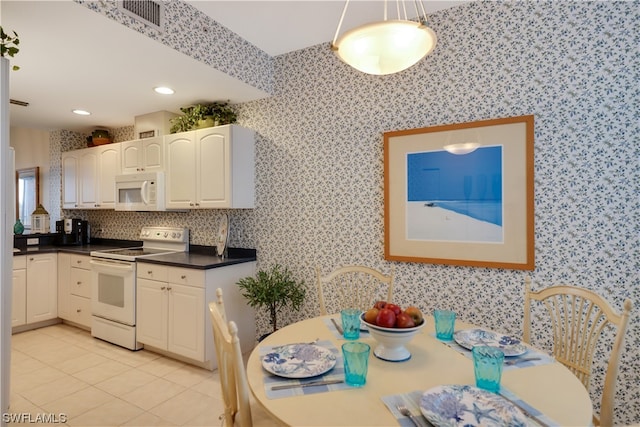 kitchen with white appliances, light tile patterned flooring, decorative light fixtures, and white cabinets