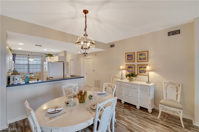 dining area featuring wood-type flooring and a chandelier